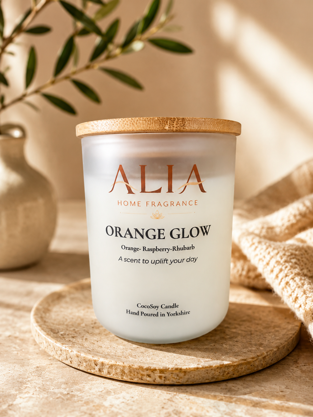 A strong, vibrant orange fragranced cocosoy candle in a frosted jar with a bamboo lid